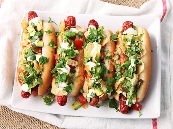 Bacon-wrapped hot dogs with avocado, tomato, onion, mayonnaise, and potato chips