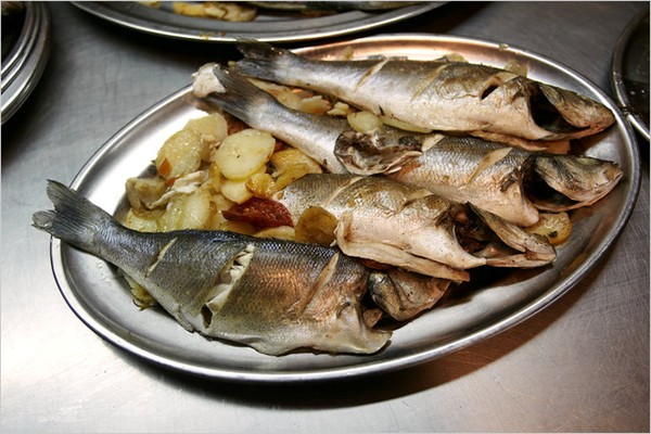 Baked sea bass with potatoes, tomatoes and onions