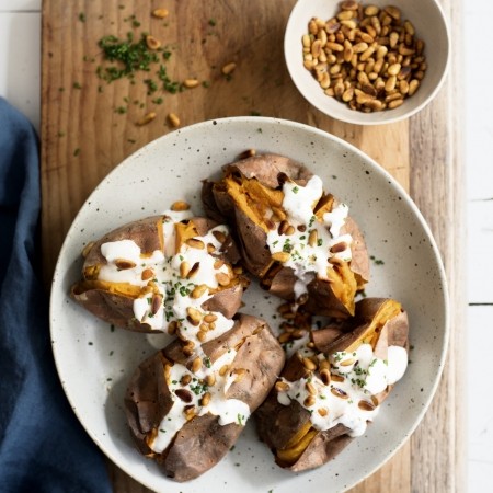 Baked sweet potatoes with coconut-yoghurt dressing and spiced pine nuts