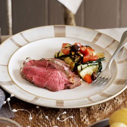 Barbecued leg of lamb with herb butter and zucchini, tomato and olive salad
