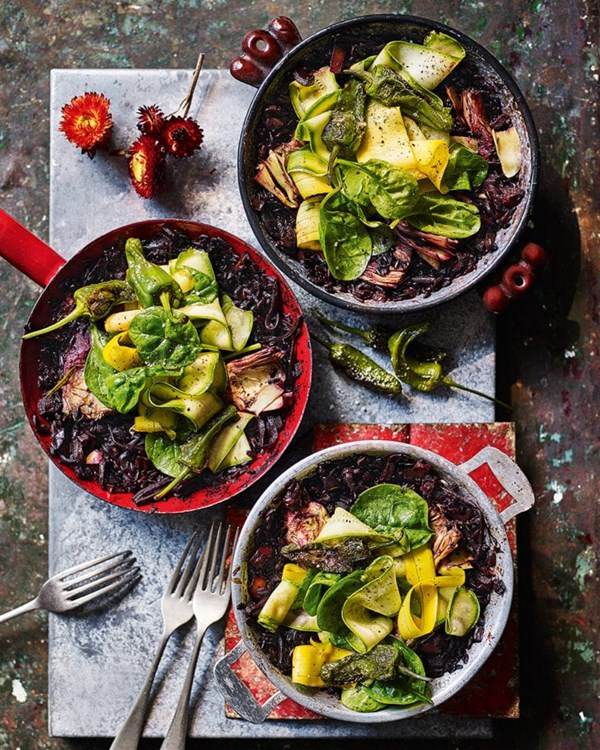 Black rice paella with artichokes, Padrón peppers and spinach