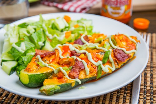 Buffalo chicken stuffed zucchini topped with melted cheddar, bacon and an avocado blue cheese dressing