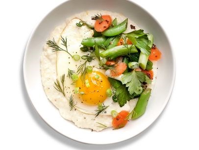 Cheesy grits with fried eggs and vegetables