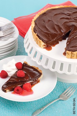 Chocolate-caramel tart with drunken raspberries and whipped cream