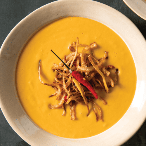 Clothbound cheddar pumpkin soup with a crispy onion, ginger, and chilies garnish