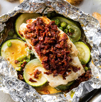 Cod baked in foil with potatoes, zucchini, and sun-dried tomatoes