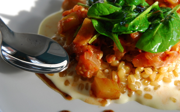 Creamy white wheat berry porridge with eggplant stew and wilted spinach