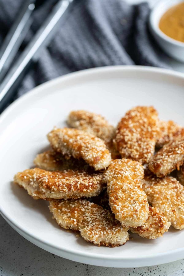 Crispy sesame chicken fingers with spicy peanut sauce