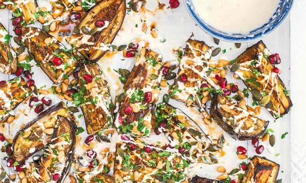Cumin-roasted aubergine wedges with pumpkin seeds, pine nuts, pomegranate seeds and yogurt dressing