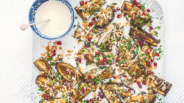 Cumin-roasted aubergine wedges with pumpkin seeds, pine nuts, pomegranate & yogurt dressing