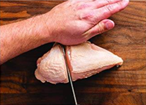 Cutting a bone-in split chicken breast in half crosswise