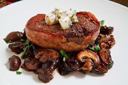 Double smoked bacon wrapped filet mignon with caramelized mushrooms topped with blue cheese