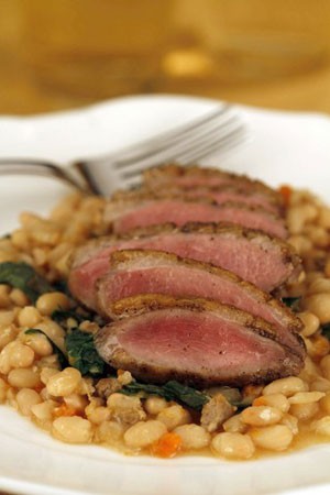 Duck breasts on white beans with dandelion greens