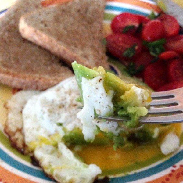 Eggs in avocado with tomato and basil