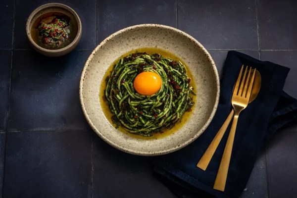 Green spaghetti with golden egg yolk and chilli gremolata
