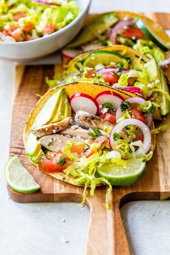 Grilled chicken tacos with lettuce slaw, avocado and cotija