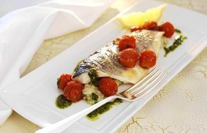 Grilled fillets of sea bass with herb risotto, roasted cherry tomatoes and pesto