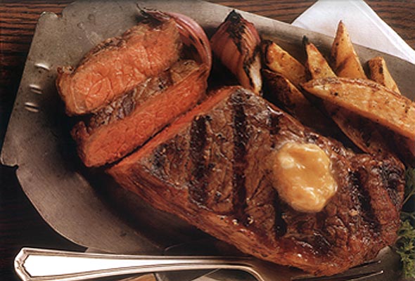 Grilled New York strip steaks with roasted garlic butter