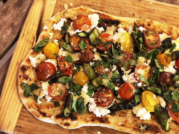 Grilled pizza with grilled tomatoes, asparagus, goat cheese, and Marcona almonds
