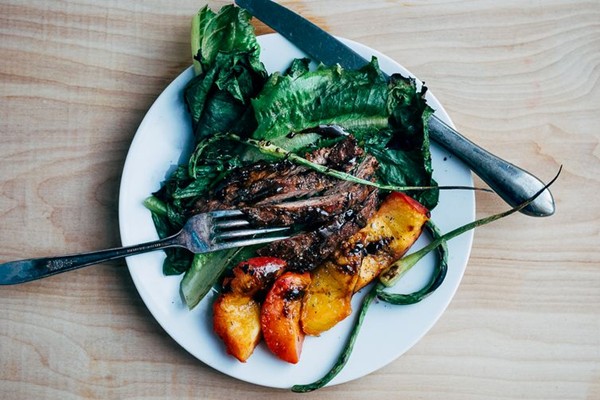 Grilled salad with romaine, peaches, garlic scapes, and steak