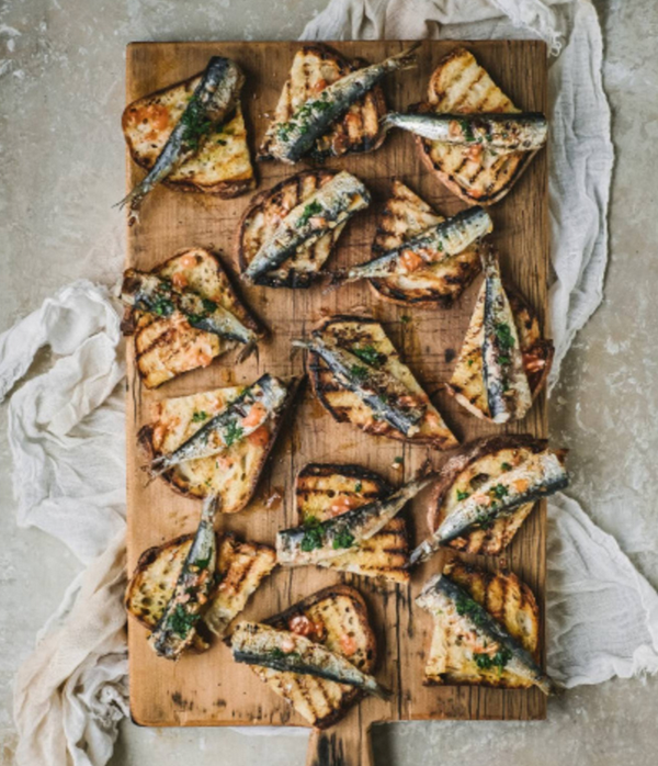 Grilled sardines with parsley, lemon zest and tomato seeds on charred bread