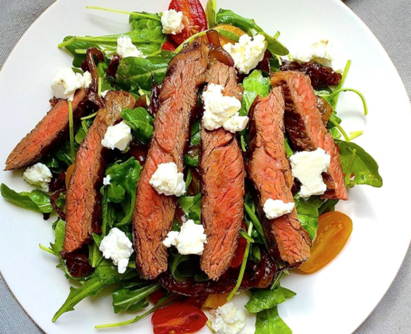 Grilled skirt steak salad with arugula, balsamic-glazed onions, tomatoes, and feta