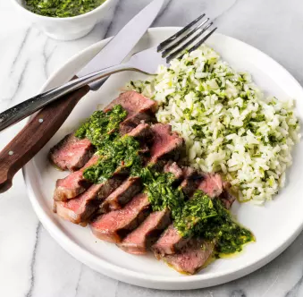 Grilled strip steaks with green rice and cilantro sauce