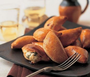Half-moon cheese pies with raisins and pine nuts