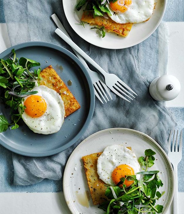 Hash browns with eggs fried in olive oil and herb salad