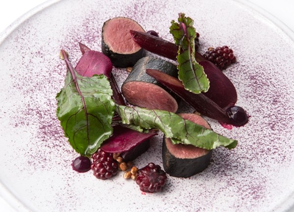 Hay smoked roe deer with red fruits, vegetables and leaves