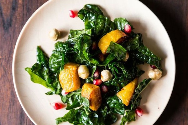Hearty kale salad with kabocha squash, pomegranate seeds, and toasted hazelnuts