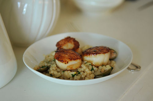 Israeli couscous with roasted lemons & capers topped with seared scallops & a lemon creme fraiche drizzle