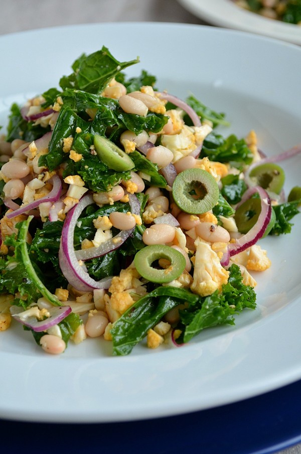 Massaged kale salad with chopped cauliflower, white beans, and green olives