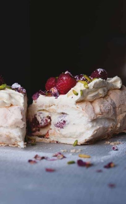 Meringue roulade with rose petals and fresh raspberries