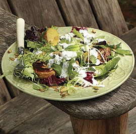 Mixed green salad with sugar-roasted peaches, lots of seeds, and creamy goddess dressing