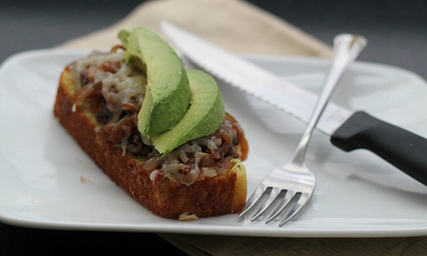 Open-faced grilled cheese with refried beans, caramelized onions and avocado on cornbread