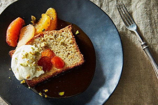 Pistachio meringue cake with fresh citrus, candied kumquats, and cardamom caramel sauce