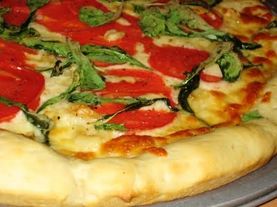 Pizza with arugula, tomatoes, and roasted garlic