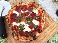 Pizza with cherry tomatoes, halloumi, olives, and mint