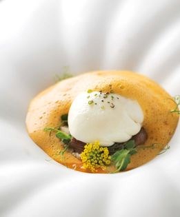 Poached farm egg with pimento nage, millet, and roasted chestnuts