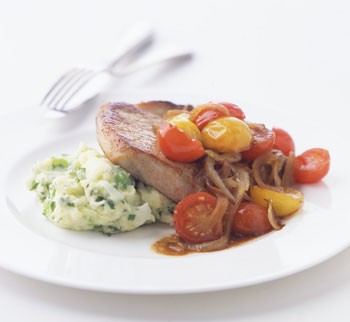 Pork chops with golden onions and wilted tomatoes