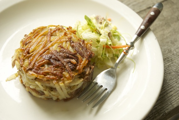 Potato and pork confit cakes with wilted napa cabbage and cress slaw