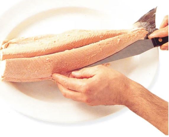 Preparing a whole poached fish for serving