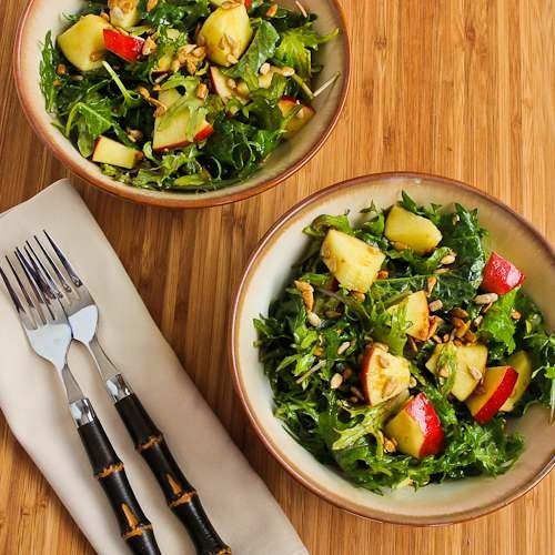 Raw baby kale salad with apples, sunflower seeds, and lemon-Dijon vinaigrette