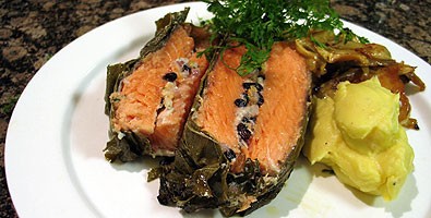 Salmon baked with a stuffing of pine nuts, currants and preserved lemon wrapped in vine leaves