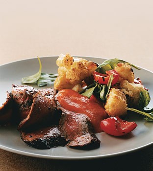 Sautéed flank steak with arugula and roasted cauliflower and red peppers