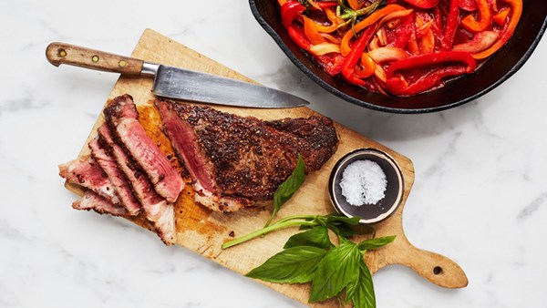 Seared strip steaks with braised peppers and onion