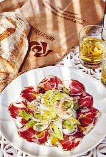 Sliced coppa with celery, green olive, and lemon