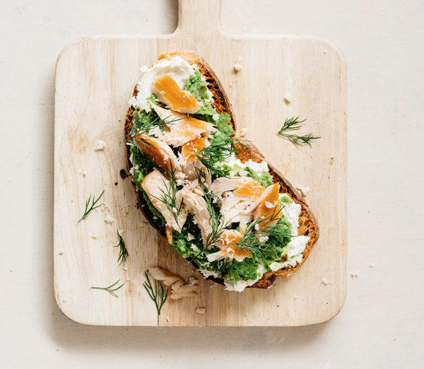 Smashed peas on toast with goat cheese, fresh horseradish, herbs, and smoked trout