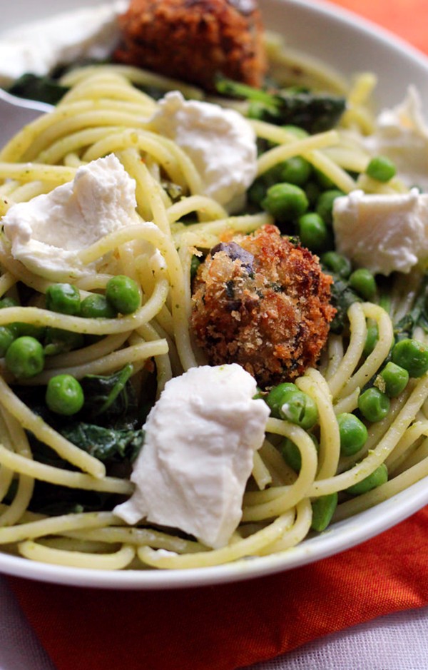 Spaghetti with eggplant balls, pesto, peas, and greens